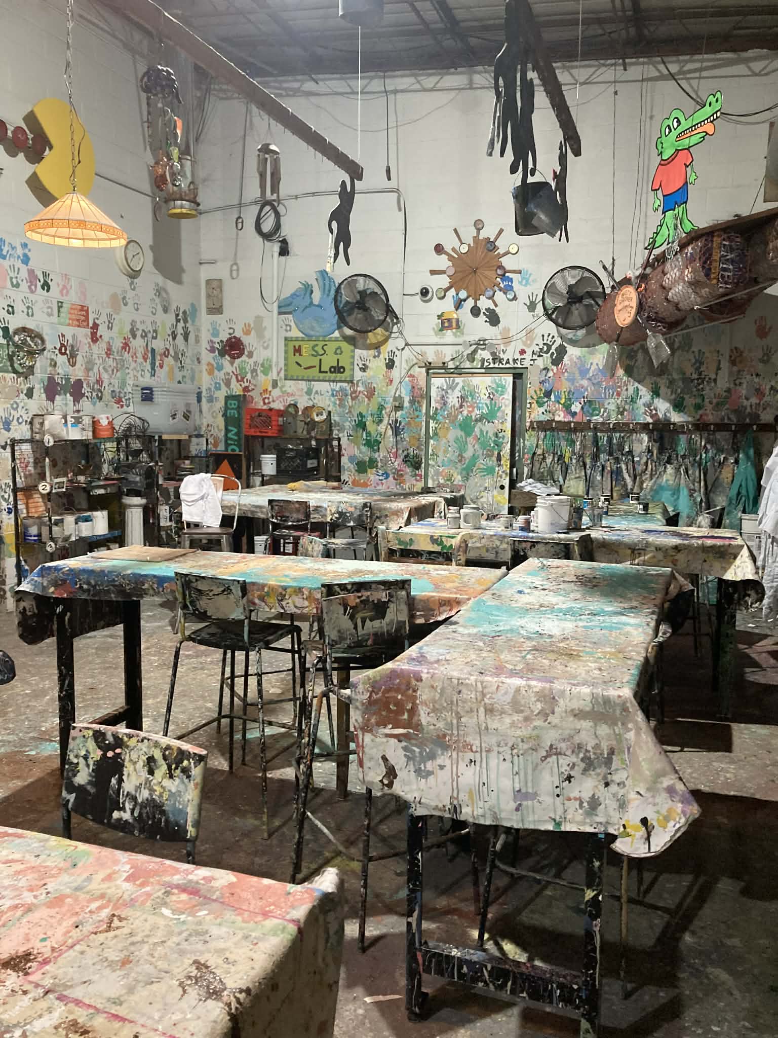 The Green Project art studio with colorful upcycled art and paint-covered tables